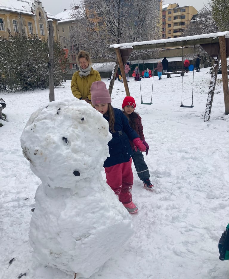 Kinder bauen einen riesigen Schneemann.