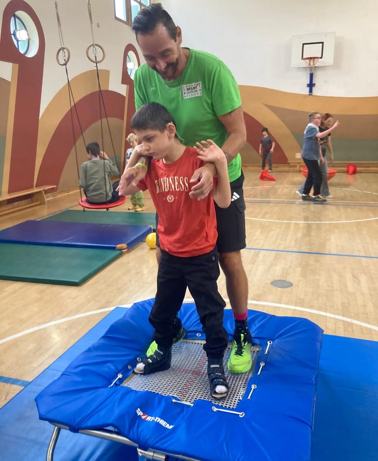 Trainer steht mit Bub auf einem Trampolin