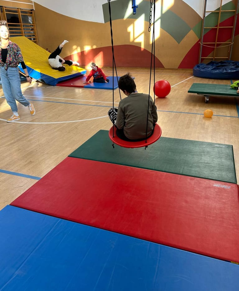 Ein Kind sitzt auf der Schaukel im Turnsaal.
